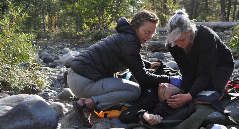 Two people tend to another during a wilderness first responder exercise. 